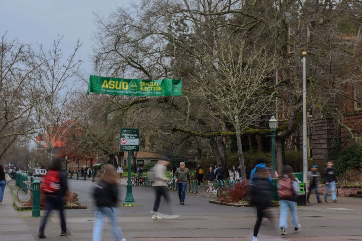 Students walking by the ASUO Special Election Banner displayed on 13th Ave. center of campus at the University of Oregon