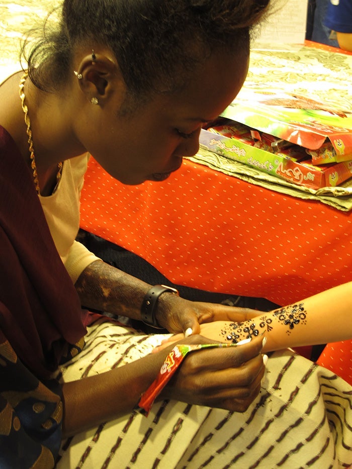 A woman applies henna to a child's arm