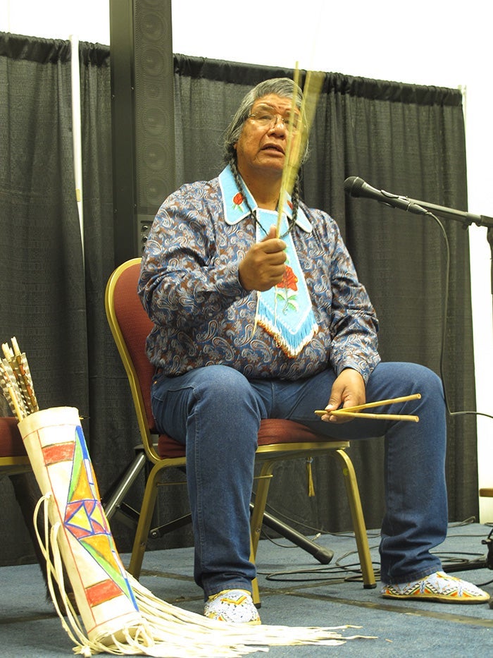 Native American man with quiver sitting on stage