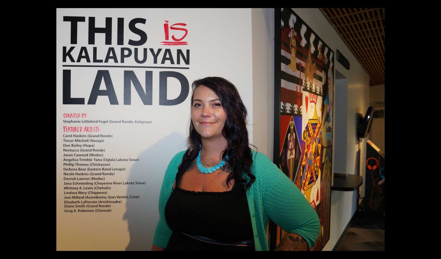 A smiling Steph LIttlebird stands in front of text reading "This is Kalapuyan Land"