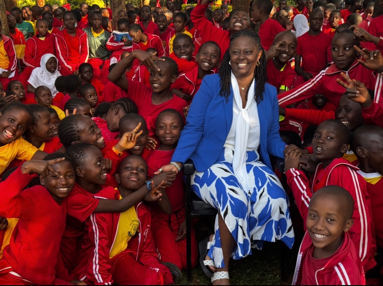 A woman in blue is surrounded by children wearing red