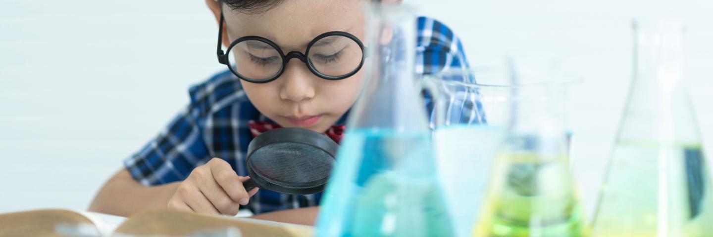 A stock photo of a child playing with some colored water in beakers