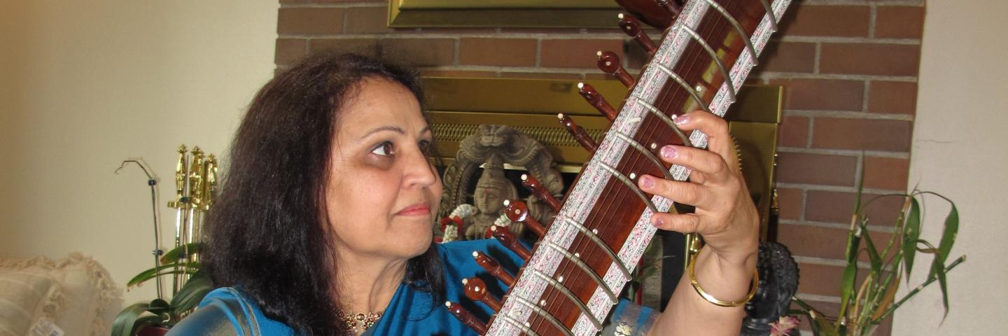 Indian woman playing stringed musical instrument.