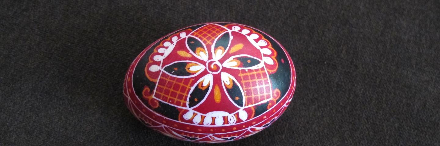 Red, white, and black painted egg against a grey background
