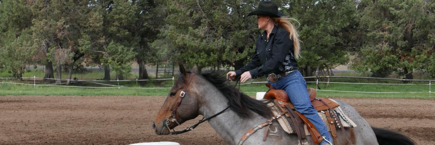 Tonya Rosebrook riding her horse around a white barrel