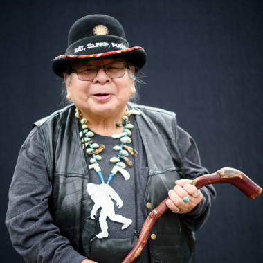 Man wearing black smiles holding a cane