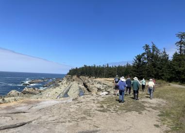 A dramatic coastal landscape with a group of adults walking away from the camera