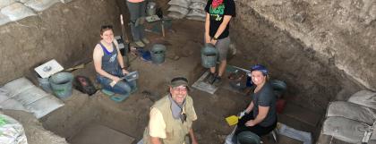 Five people working in a dig pit with sand bags around them.