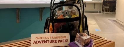 Clear backpack filled with activities sitting on a bench in the museum.