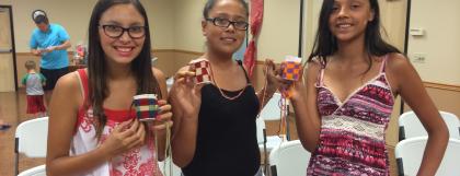 Three girls hold their handmade baskets
