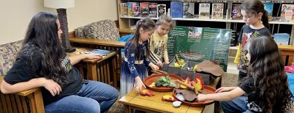 A family of three children and a mother from Confederated Tribe of Grand Ronde use the camas oven activity
