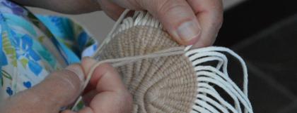Close up of hands weaving a basket