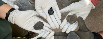 Five hands holding stone tools in a circle
