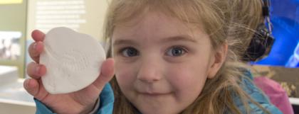 A child showing a fossil imprint craft