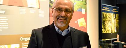 Volunteer Rafael smiles in front of a geology exhibit.