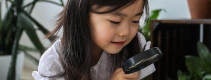 a child examining a leaf under a microscope