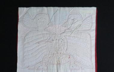Reverse of mola with birds and a human face on white cloth