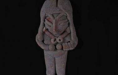 Female Human Figurine with Bone Necklace (front). Locks of filleted hair falling down over the ears reveal the fronts of large earrings. Buff earthenware, unpolished, traces of red and white paint.