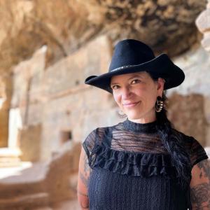 Chelsea rose smiles in front of a blurred, vaguely historically architectural background