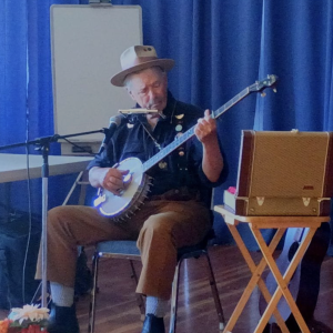 A sitting man plays the banjo.