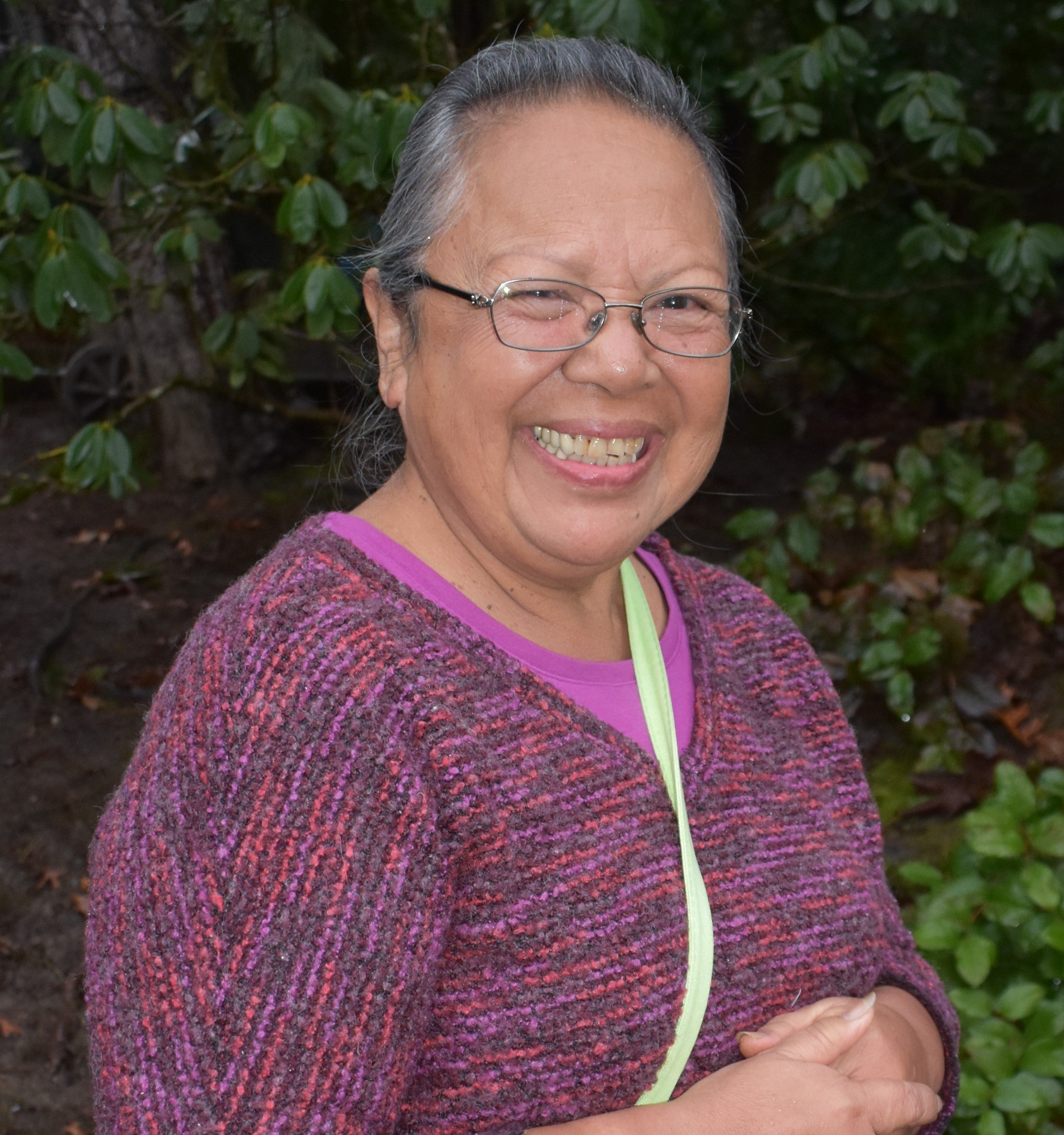 old native american woman smiling wearing a pink sweater