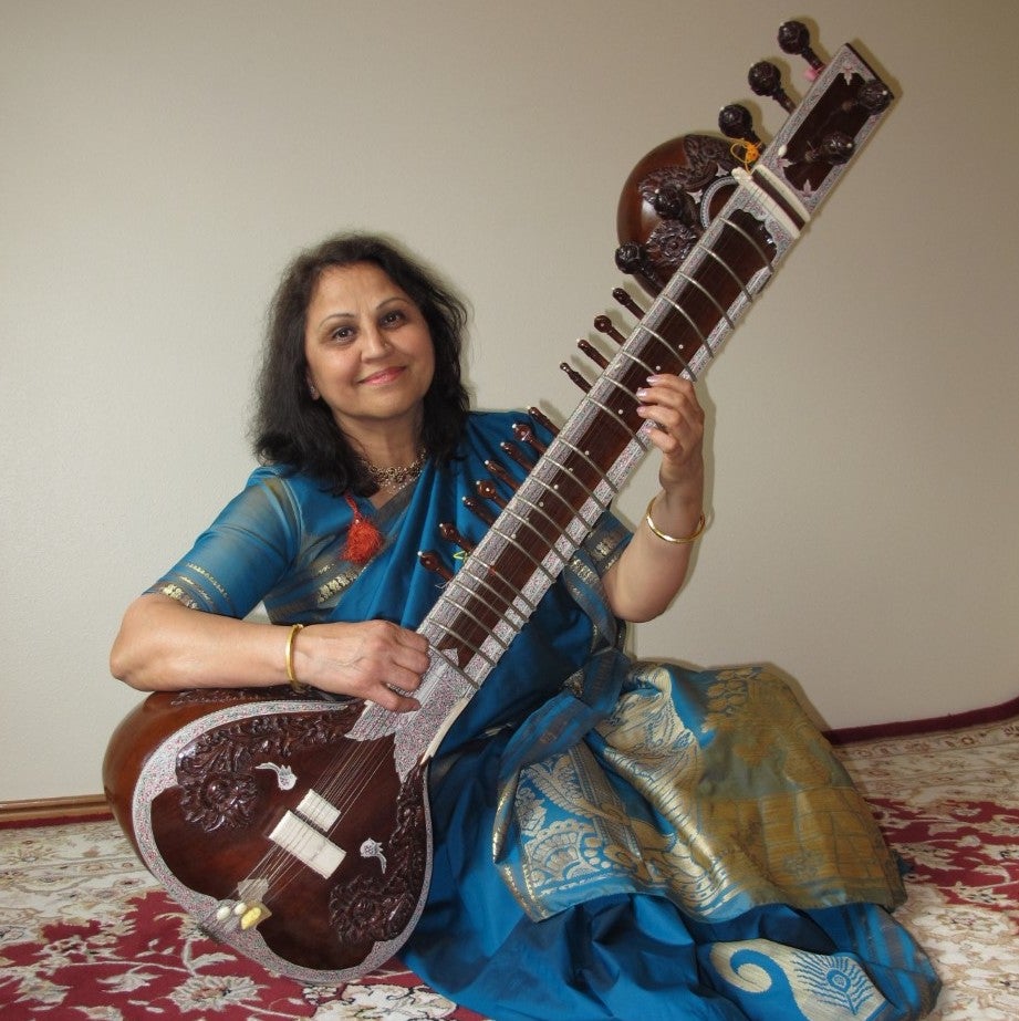 Photo of Nisha Joshi, an Indian woman seated with a sitar.