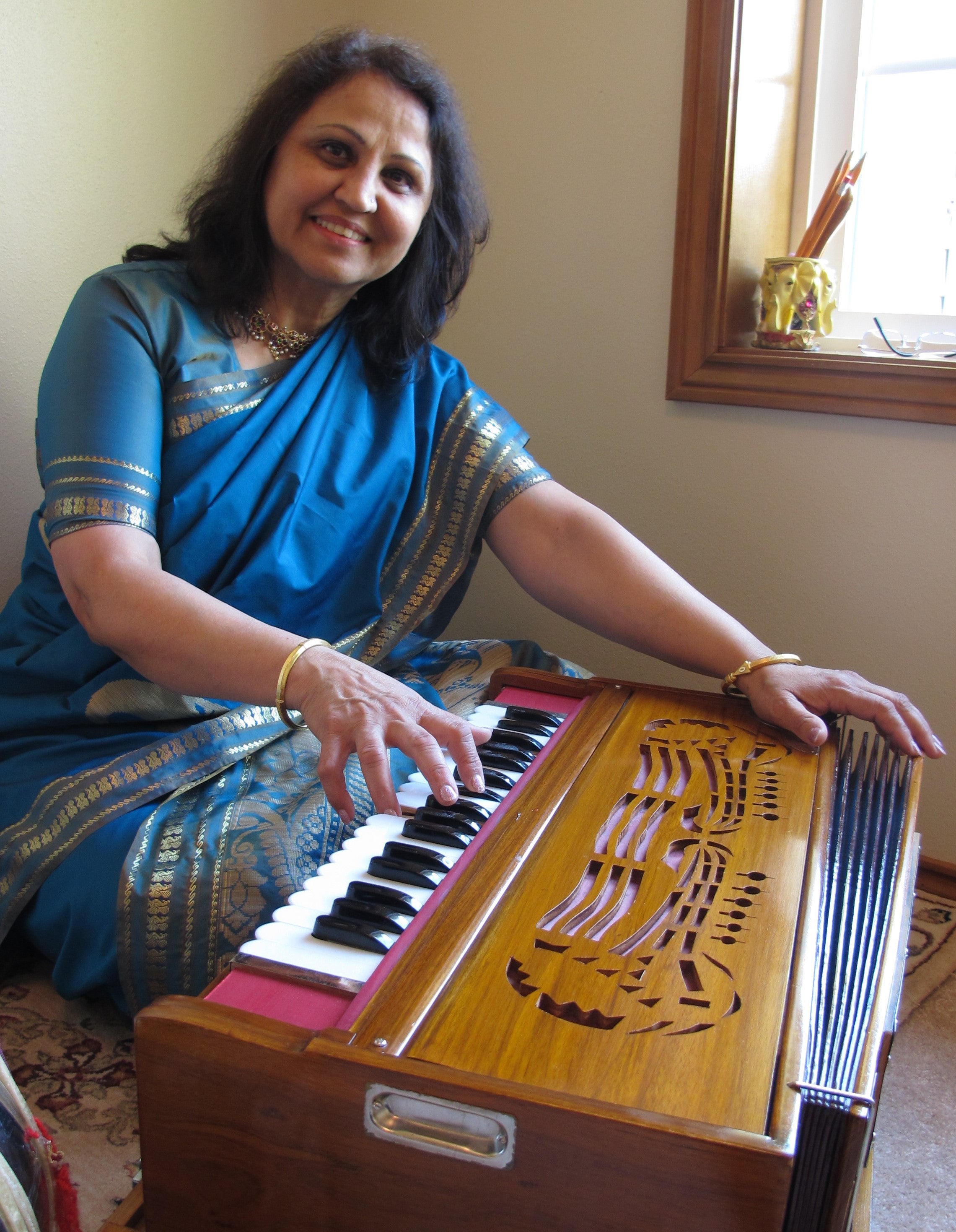 Indian woman playing musical instrument and smiling at the camera