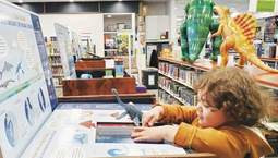 A small child plays with a hands-on dinosaur exhibit