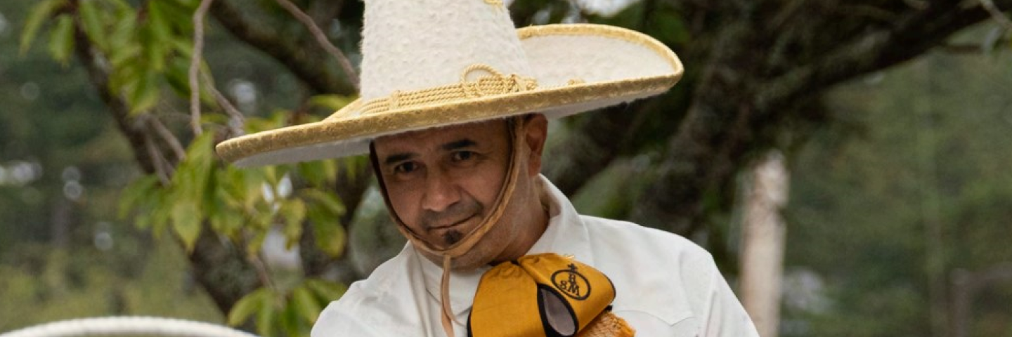 mexican man in a white shirt and sombrero throwing a lasso rope