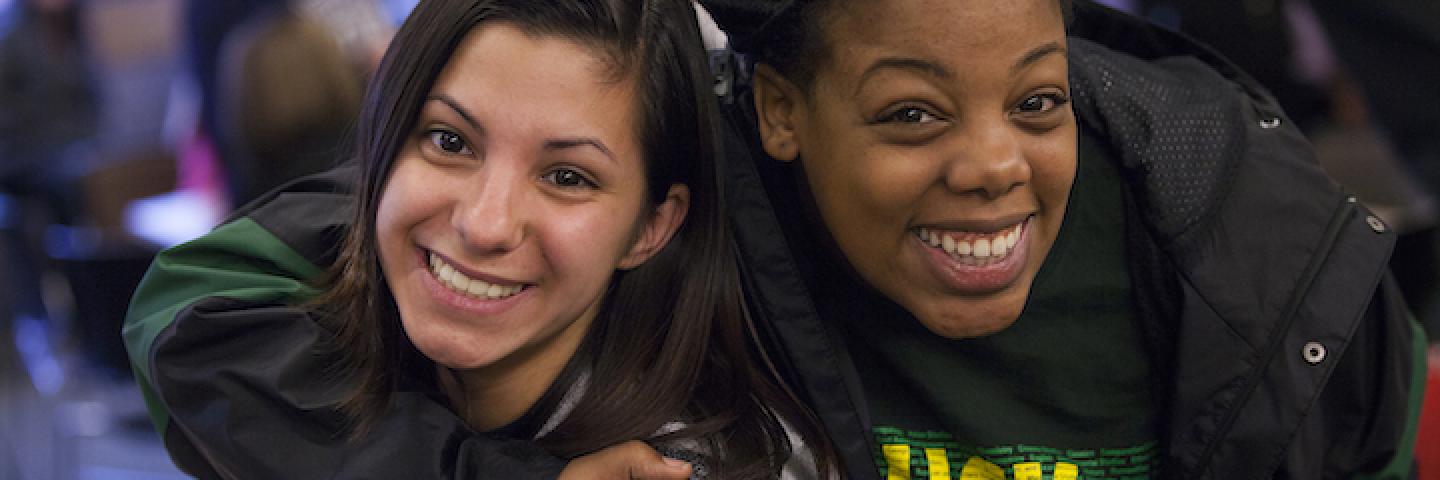 two students smiling at the camera, one with an arm around the other.