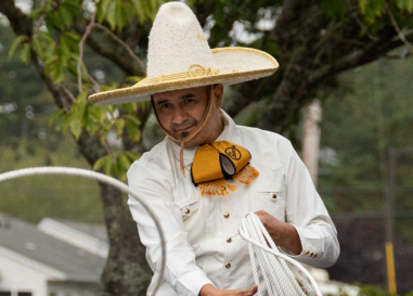 mexican man in a white shirt and sombrero throwing a lasso rope