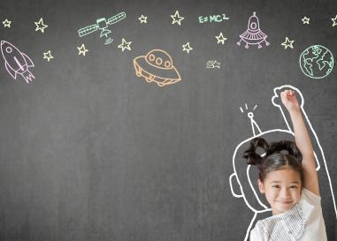 Smiling child poses with a chalkboard covered in whimsical science-related imagery