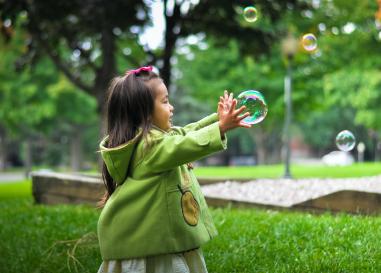 Little girl reaching for a bubble outside