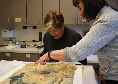 Mexican historian Lidia Gómez García examines a Latin American mapa with UO researcher Stephanie Wood. 