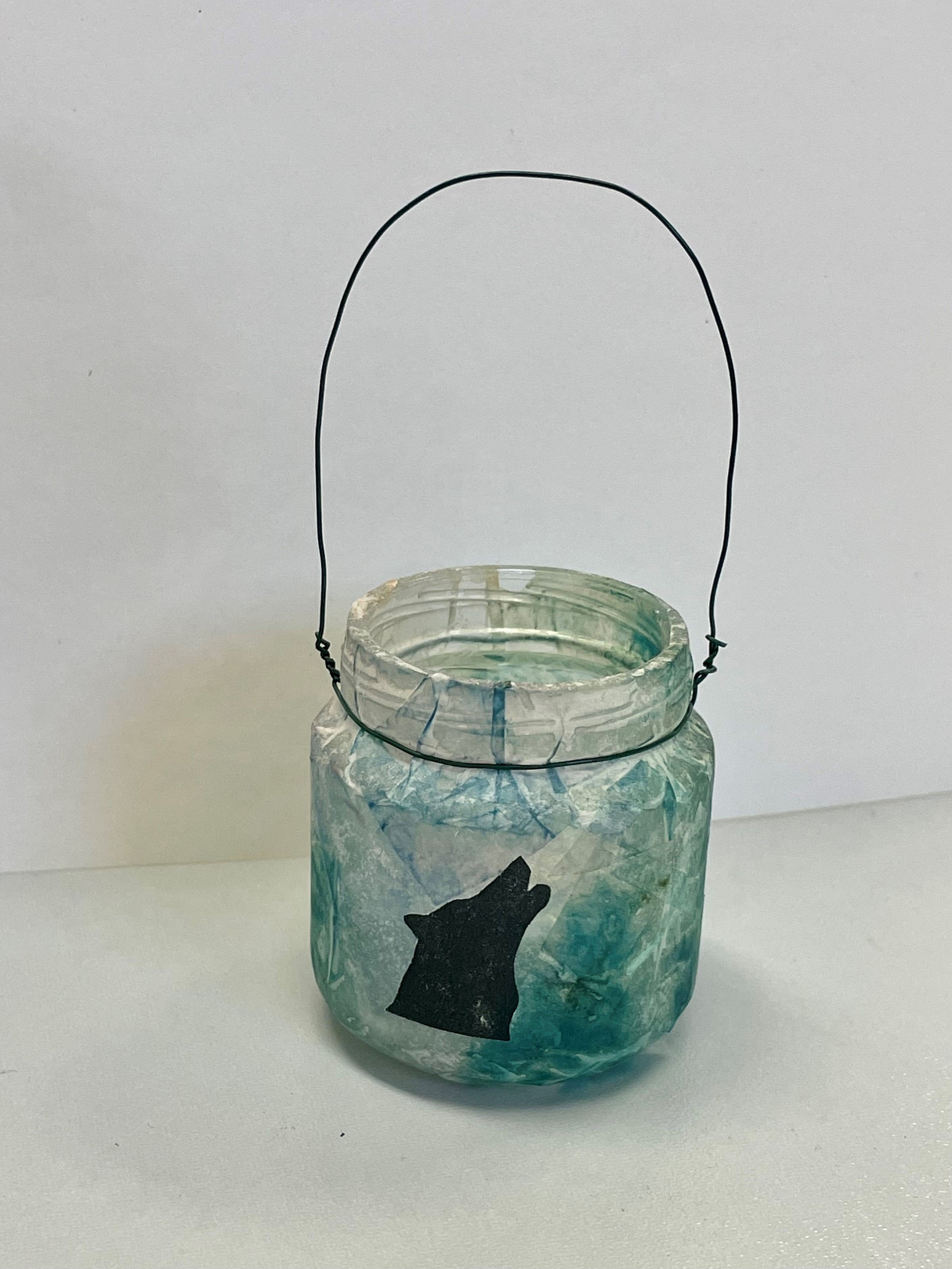 glass jar covered in tissue paper with a wolf on it