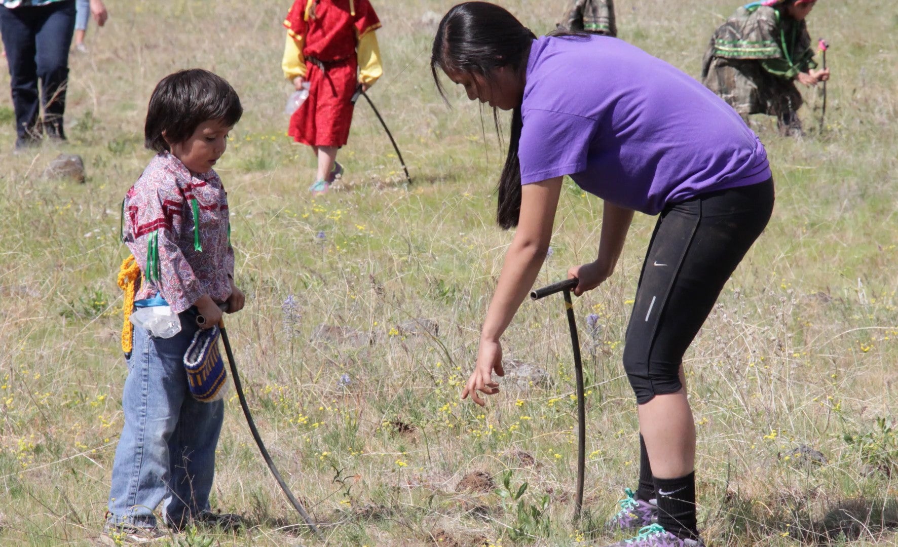 A woman teaching a child to dig for camas